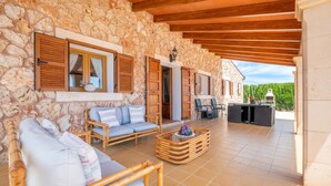 Una stanza con pareti in pietra e soffitto in legno, un divano, un tavolino da caffè e vista su un paesaggio verde.
