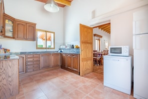 A kitchen with wooden cabinets, a built-in microwave, and a refrigerator.