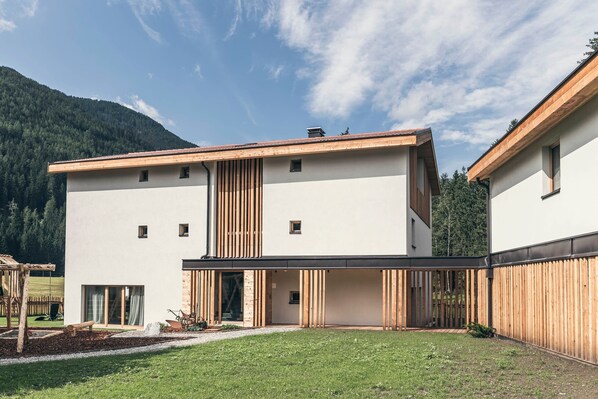 A modern building with a flat roof, large windows, and a wooden deck. - Apartment "Lichtung Woldererhof Auszeit" with Mountain View, Sauna & Balcony (Racines)