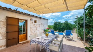 Un patio al aire libre con mesa lista para comer, un área de estar cubierta y vistas a una piscina.