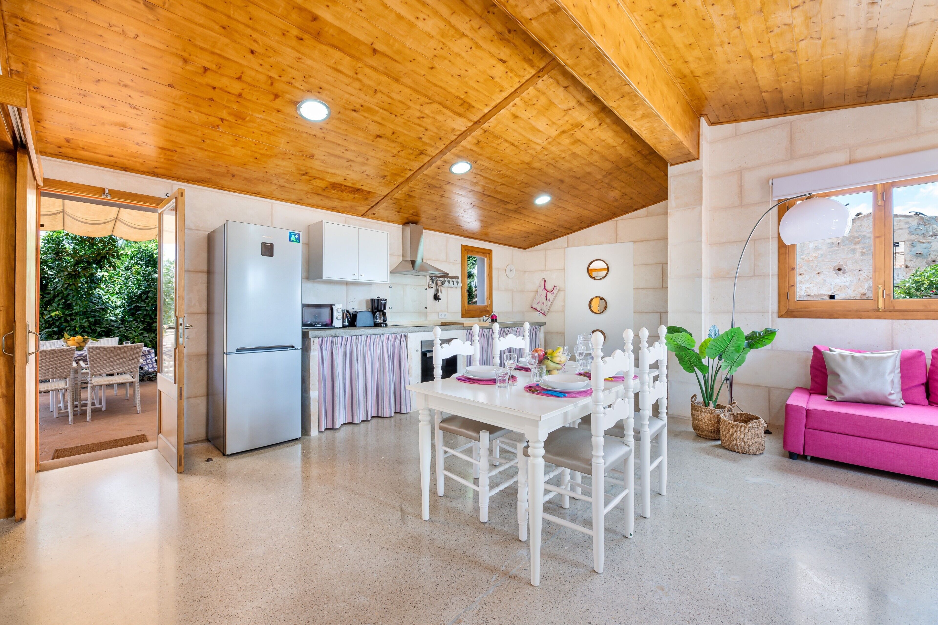 A kitchen with a refrigerator, stove, and dining table set for four.
