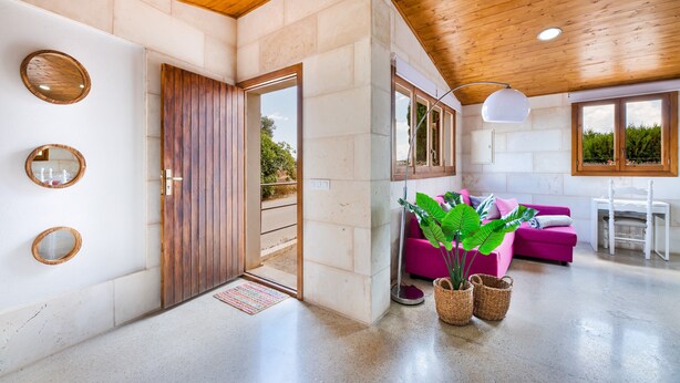 Un interior moderno con techo de madera, un sofá rosa y una zona de comedor.