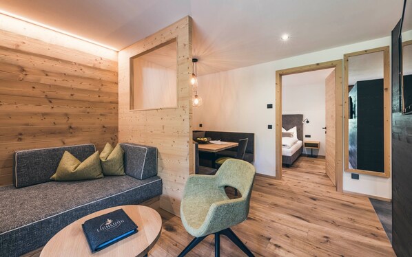 A modern interior with a wooden wall, a sofa with cushions, a round table with a book, and a chair.