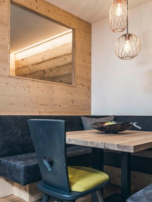A modern dining area with a wooden ceiling, a large mirror, and two pendant lights.