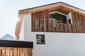A modern building with a sloped roof, wooden exterior, and large windows.