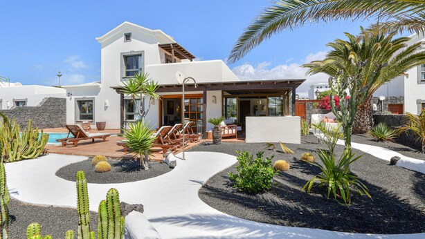 A modern house with a pool, outdoor seating, and a well-maintained garden with cacti and palm trees. - Villa "Marta" with Pool, Garden, and Terrace (Playa Blanca)