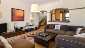 A modern living room with a sofa, coffee table, TV, and artwork. - Villa "Marta" with Pool, Garden, and Terrace (Playa Blanca)