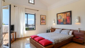 A bedroom with a bed, a TV, a window, and artwork on the wall. - Villa "Marta" with Pool, Garden, and Terrace (Playa Blanca)