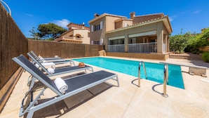 A swimming pool with lounge chairs, a wooden deck, and a building with balconies.