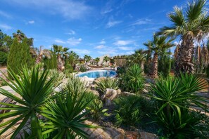 Une piscine entourée de plantes tropicales et bordée d’une structure en pierre.