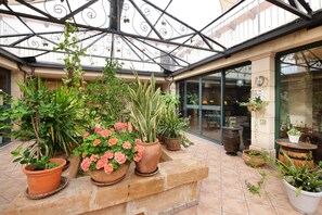 A covered patio area with potted plants, a stone bench, and a glass door leading to an interior space. - Finca "Melongos" with Mountain Views, Pool, Wi-Fi, Terraces and Garden (Inca)