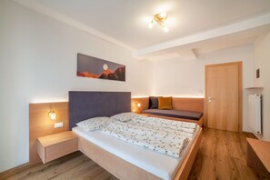 Une chambre à coucher comprenant un lit, des tables de chevet, une commode, un canapé, une porte et un tableau accroché au mur.