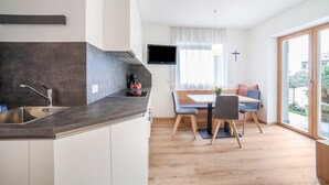 Eine moderne Küche mit Einbauherd, Spüle und einem flachbildfernseher an der Wand.
