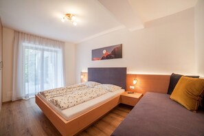 A modern bedroom with a bed, bedside tables, a sofa, a window with curtains, and a wall-mounted painting. - Apartment "Haus Hohenrain 1" with Mountain View, Pool, Wi-Fi, Terrace & Garden (Schenna)