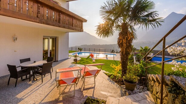 Ein Balkon mit Holzausleger, ein Pool und Blick auf einen Berg.