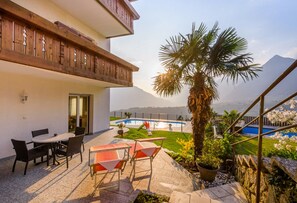 A balcony with wooden railings, a pool, and a view of a mountain. - Apartment "Haus Hohenrain 1" with Mountain View, Pool, Wi-Fi, Terrace & Garden (Schenna)