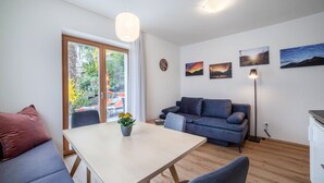Ein modernes Wohnzimmer mit Sofa, Esstisch und Kunstwerken an den Wänden.