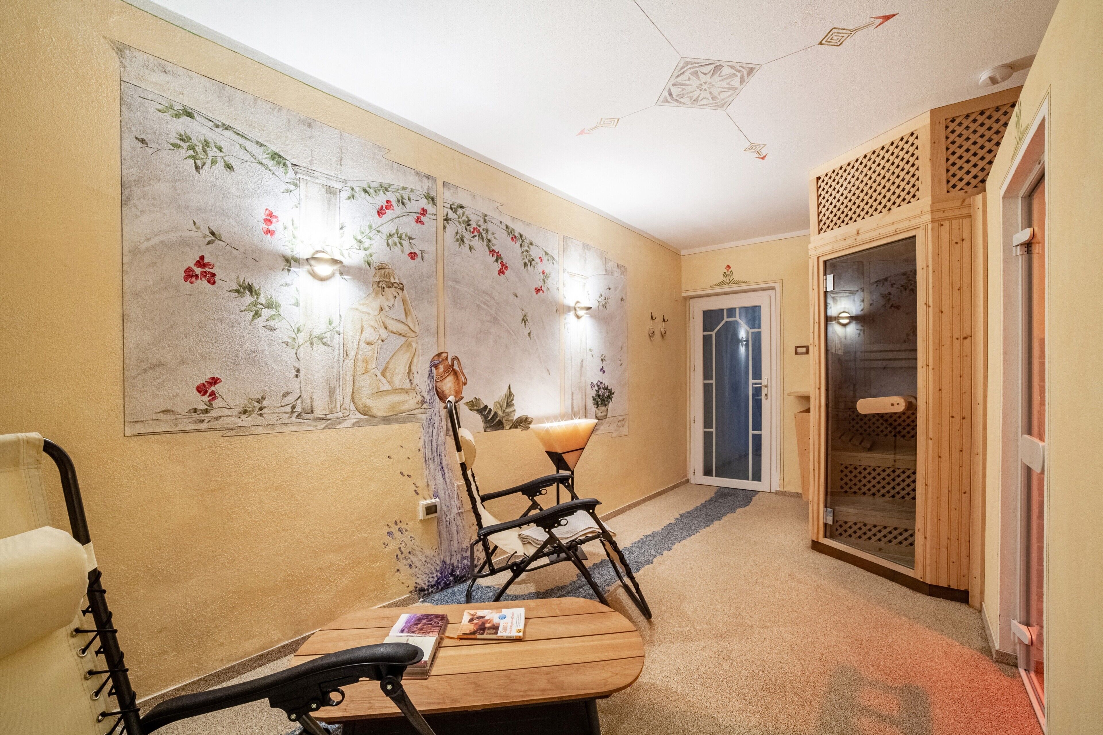 A hallway with a traditional mural, a wooden bench, a chair, and a sauna door.