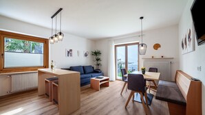 A modern living room with a sofa, coffee table, dining table, and bench. - Apartment "Haus Hohenrain 2" with Mountain View, Pool, Wi-Fi, Terrace & Garden (Schenna)