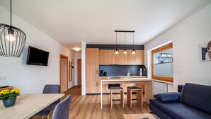 A modern kitchen with wooden cabinets, a central island, and pendant lighting. - Apartment "Haus Hohenrain 2" with Mountain View, Pool, Wi-Fi, Terrace & Garden (Schenna)