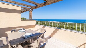 Un balcon avec une table dressée pour le dîner, offrant une vue sur la côte.