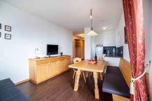 A compact kitchen with wooden cabinets, a dining table, and a bench. - Apartment "Haus Hohenrain 4" with Mountain View, Pool, Wi-Fi, Balcony & Garden (Schenna)