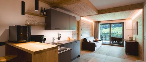 A modern kitchen with wooden beams, a central island, and a dining area with a view.