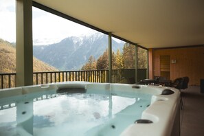 Ein Whirlpool mit Blick auf die Berge, Holzwände und ein Balkon mit Stühlen.