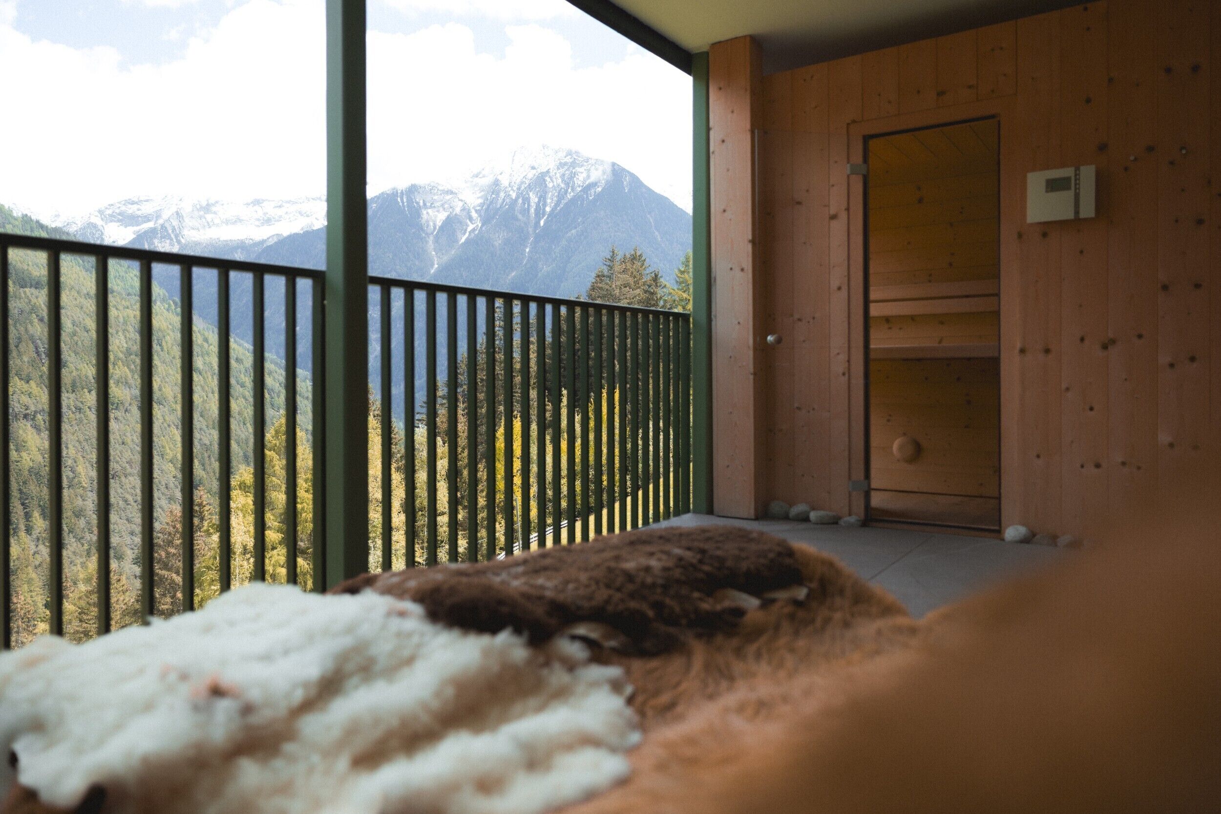 Habitación con balcón que da a las montañas, una puerta de madera y un estante pequeño.