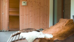 Une cabane en bois avec un banc, une porte en bois et une porte coulissante en verre.