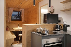 A modern kitchen with wooden walls, a built-in stove, a microwave, and a coffee maker.