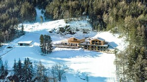 Un chalet au design moderne, entouré d’une forêt enneigée.