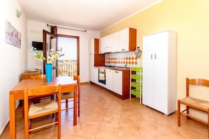 A compact kitchen with a dining area, a TV, and a balcony with a view.