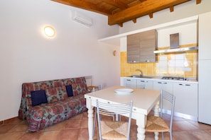 A compact kitchen with a dining table, chairs, a sofa, and a built-in stove. - Holiday Apartment "Case Aquafan Mare 1" with Sea View, Mountain View, Pool and Terrace (Isola Rossa)