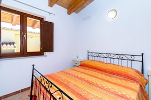 A bedroom with a bed, wooden ceiling, window, and a nightstand. - Holiday Apartment "Case Aquafan Mare 1" with Sea View, Mountain View, Pool and Terrace (Isola Rossa)