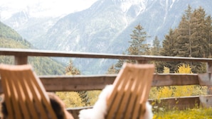 A wooden deck with two chairs facing a mountainous landscape. - Apartment "Archehof Hochzirm Lodge Franz" with Mountain View, Sauna & Terrace (Campo Tures)