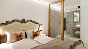 A modern hotel room with a large bed, a glass-enclosed shower, and a wooden headboard. - Apartment "Archehof Hochzirm Lodge Franz" with Mountain View, Sauna & Terrace (Campo Tures)