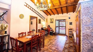 Un'area pranzo con un tavolo e sedie in legno, un lampadario e una scala che conduce a un'altra stanza.