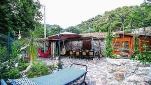 Zona patio con amaca, mobili da esterno e muretto in pietra.