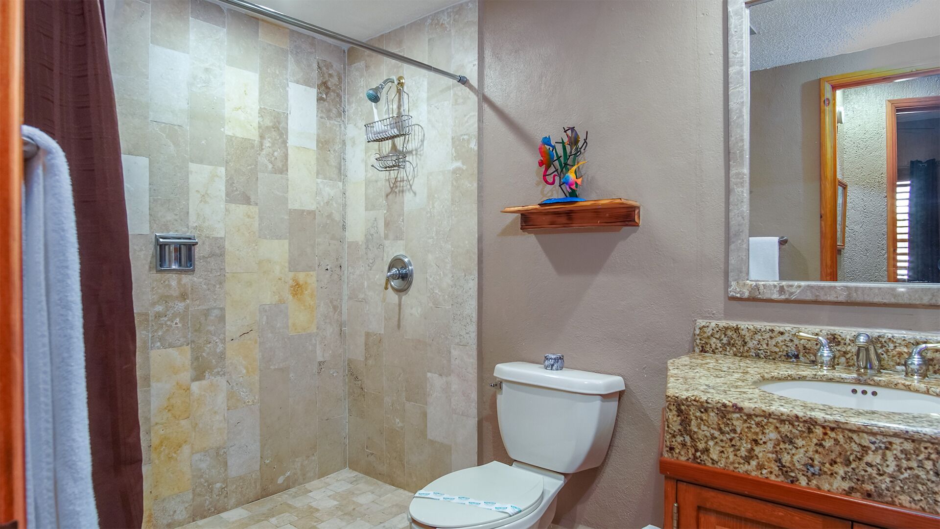 A bathroom with a shower, toilet, sink, and a mirror.