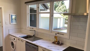 A modern kitchen with a built-in dishwasher, a double sink, and a stove. - Twin Cedars Cottage, Havelock North (Havelock North)