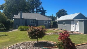 A residential property with a house and a garage, surrounded by a well-maintained lawn and garden. - Twin Cedars Cottage, Havelock North (Havelock North)
