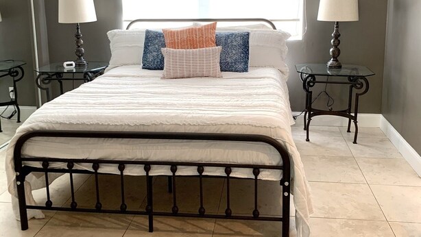 A bedroom with a large bed, two bedside tables with lamps, a window, and a view of the outside. - Citrus Cottage in Old Town Orange near Chapman U & Disneyland  (Orange)