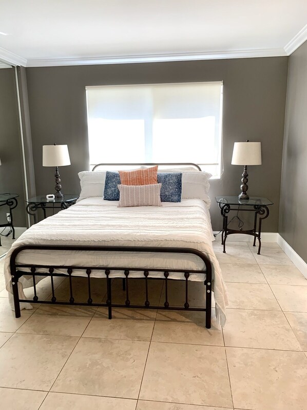 A bedroom with a large bed, two bedside tables with lamps, a window, and a view of the outside. - Citrus Cottage in Old Town Orange near Chapman U & Disneyland (Orange)