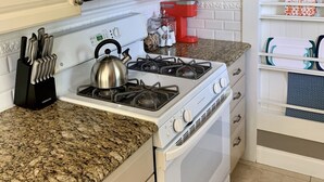 A kitchen with white cabinets, a stainless steel microwave, a gas stove, and a coffee maker. - Citrus Cottage in Old Town Orange near Chapman U & Disneyland  (Orange)