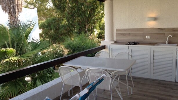 Un patio exterior con mesa y sillas, un lavamanos y una terraza de madera.
