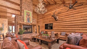A log cabin interior with a stone fireplace, leather furniture, and a mounted deer head. - Grand Mountain Retreat in Angel Fire w/ Game Room! (Eagle Nest)