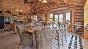 A rustic wooden cabin interior with a dining area, kitchen, and large windows. - Grand Mountain Retreat in Angel Fire w/ Game Room! (Eagle Nest)
