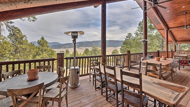 A wooden deck with tables and chairs, overlooking a mountainous landscape. - Grand Mountain Retreat in Angel Fire w/ Game Room! (Eagle Nest)