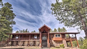 A log cabin with a wooden exterior, a stone foundation, and a porch with railings. - Grand Mountain Retreat in Angel Fire w/ Game Room! (Eagle Nest)